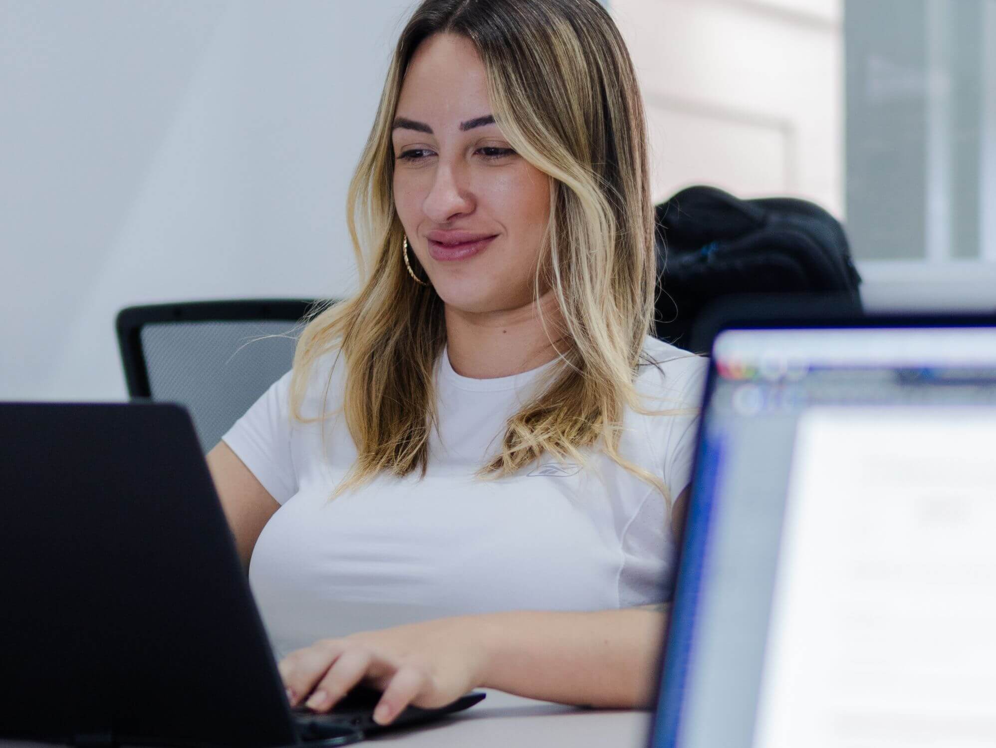 Mujer sonriente frente al ordenador ilustrando cómo solicitar financiación con un proceso seguro y transparente
